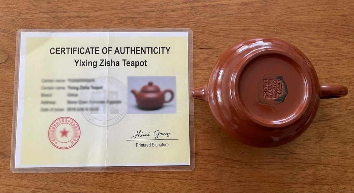 Fake authentication certificate next to counterfeit Yixing teapot.